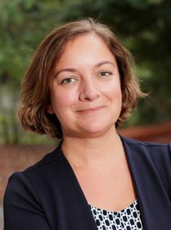 Dr. Aslan smiles for a headshot in a navy blazer with a white and navy blouse. 