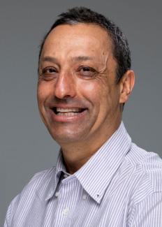 Dr. Emmanuel Boss smiles at the camera in a white collared shirt with close cropped hair. 