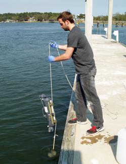 UGA Skidaway Institute grad student Sean Anderson collects a water sample from the Skidaway River. 