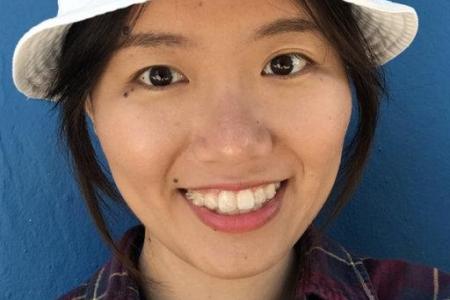 Dr. Yuting Zhu smiles broadly into the camera wearing a plaid button up and white hat. 