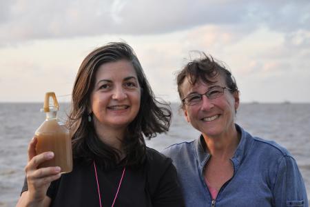 The University of Georgia’s Patricia Yager, left, and Debbie Steinberg of the Virginia Institute of Marine Sciences hold up a sample of water collected at the mouth of the Amazon River