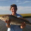 Dr. Ziegler stands center frame smiling and holding a large red drum fish