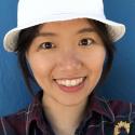 Dr. Yuting Zhu smiles broadly into the camera wearing a plaid button up and white hat. 