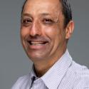 Dr. Emmanuel Boss smiles at the camera in a white collared shirt with close cropped hair. 